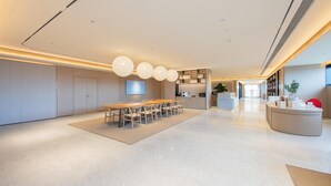 A spacious, modern hotel lobby with a central dining area, a reception desk, and a large flat-screen TV mounted on the wall. - Ji Guangzhou Nansha Phoenix Avenue Huanyu City (Guangzhou)