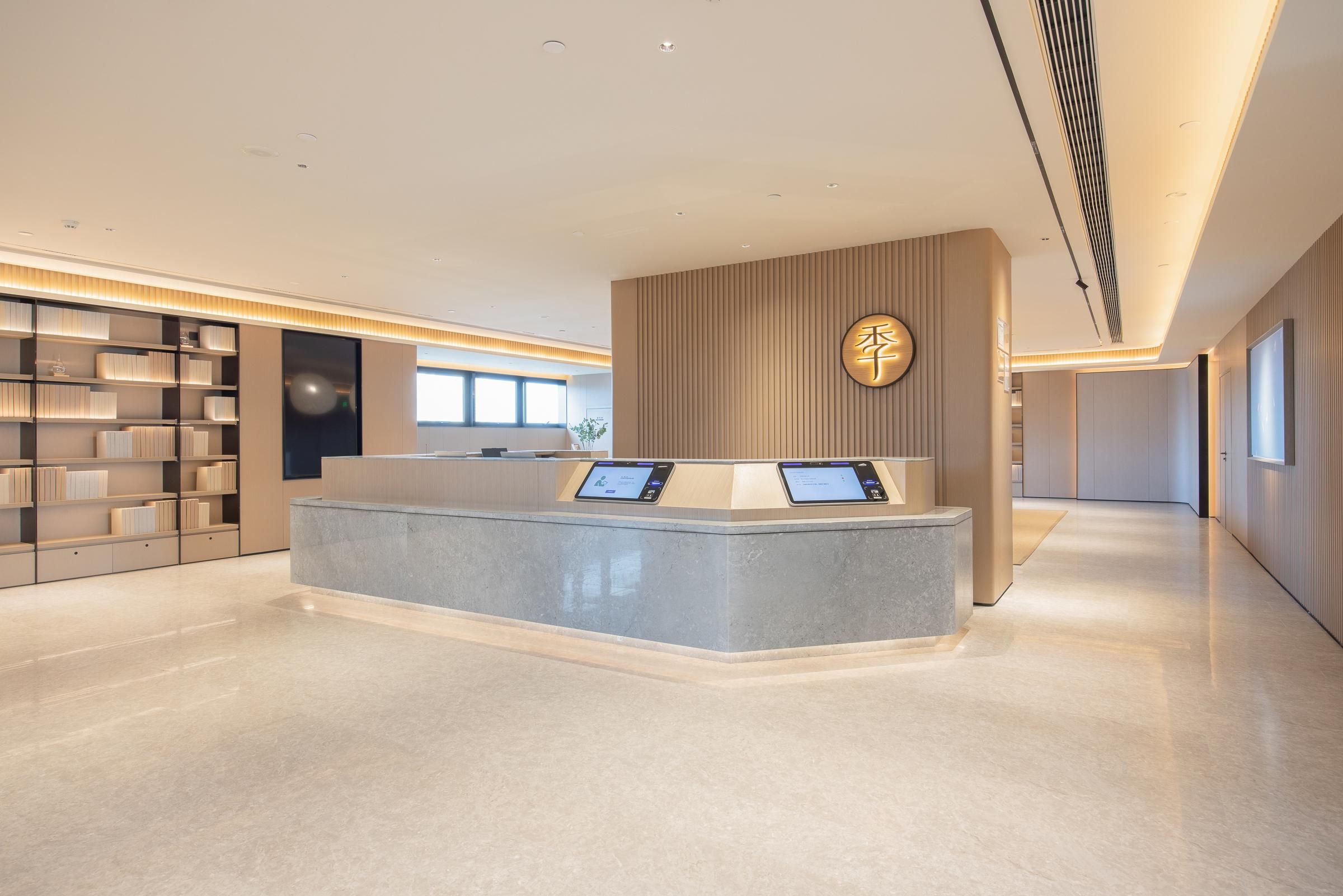 A modern reception area with a central counter, digital displays, and a wall-mounted clock.