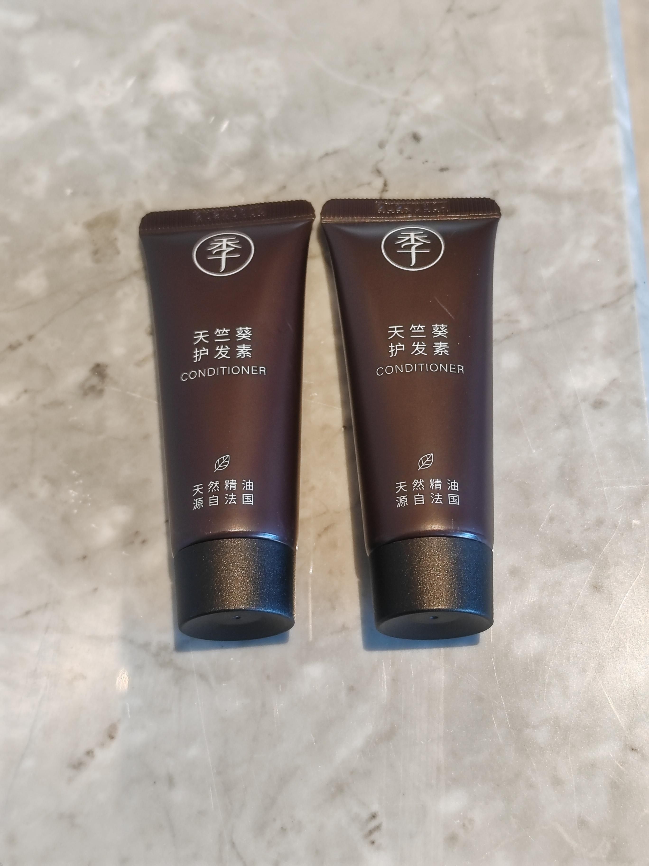 Deux tubes bruns de revitalisant, ornés de texte en chinois et d’un symbole représentant une feuille, sont posés sur une surface en marbre.
