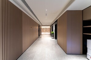 Pasillo moderno de hotel con un camino recto, iluminación empotrada y una planta en el centro.