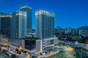 A modern hotel with multiple high-rise buildings, featuring a prominent glass facade and illuminated signage.