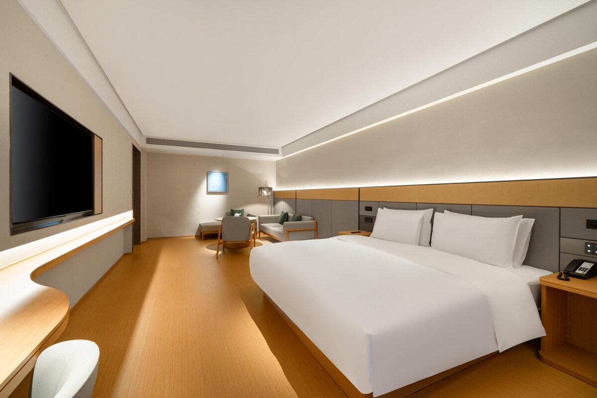 Een moderne hotelkamer met een groot bed, een bureau, een flatscreen televisie en een nachtkastje met een telefoon.