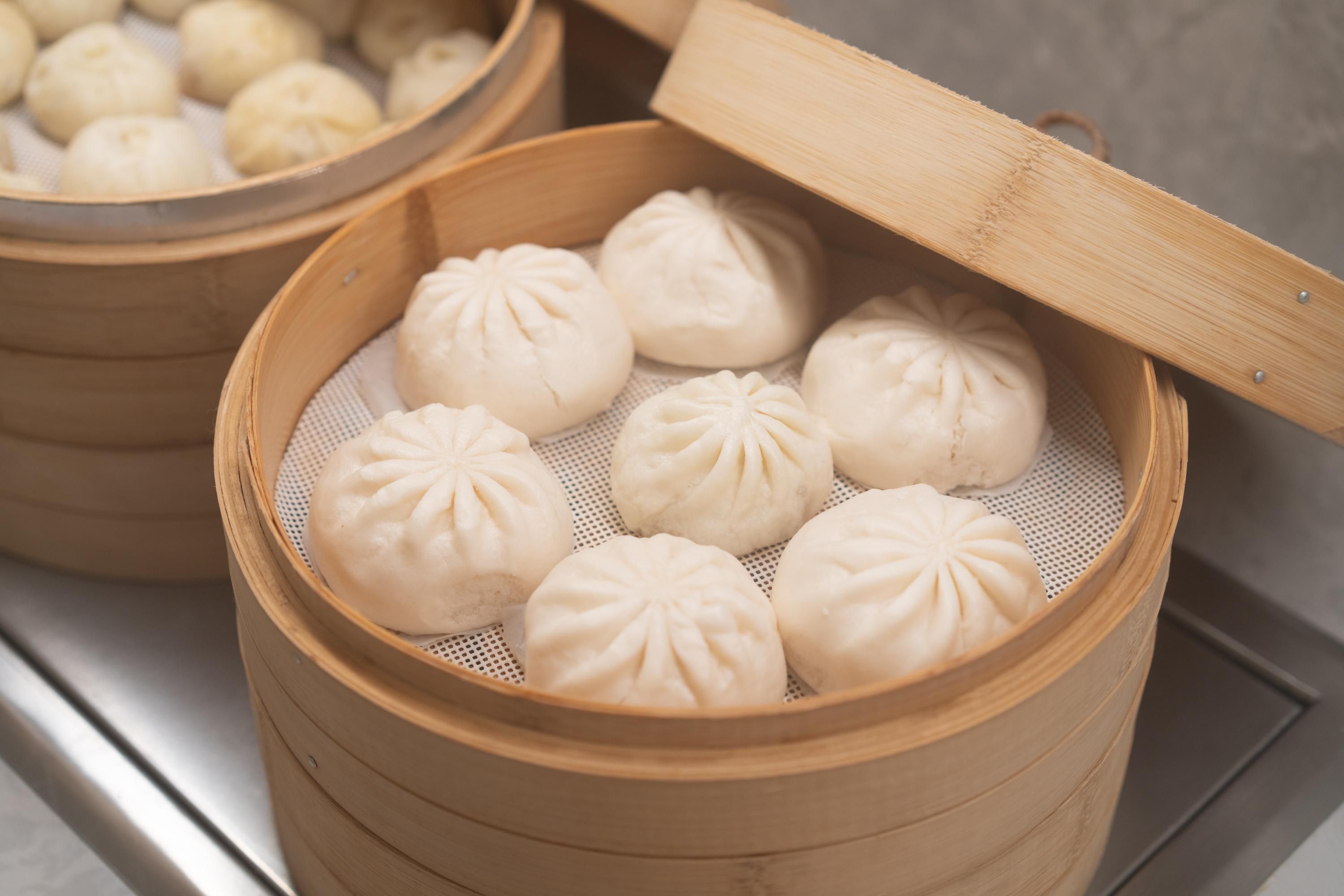 A steamer basket with several steamed buns.