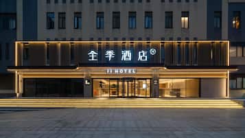 Fachada moderna de un hotel con señalización iluminada y un acceso despejado.