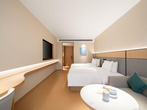 A hotel room with two beds, a TV, a bedside table, and a small seating area. - Ji Guangzhou Liwan TCL Yunfeng Technology Park (Guangzhou)