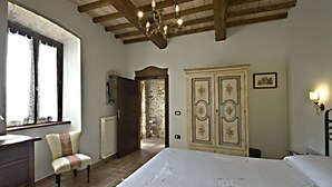 Une chambre à coucher avec un grand lit, un plafond en bois, une fenêtre, une chaise et une armoire.