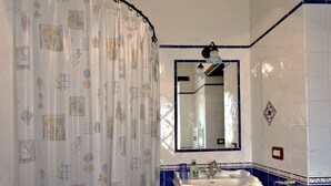 Une salle de bain avec un rideau de douche, un lavabo, un miroir et des murs recouverts de carreaux bleus.