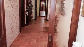 Un couloir carrelé mène à une porte, et un radiateur est placé sur le côté droit.