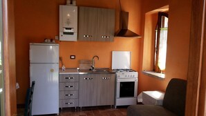 A compact kitchen with a refrigerator, stove, sink, and cabinets. - DEPENDANCE ON THE GARDEN (Uncinano, Spoleto)