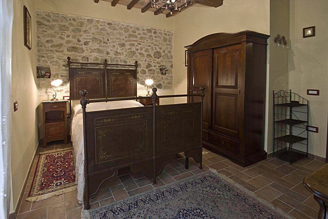 Camera da letto con parete in pietra, letto in legno, comodini e armadio.