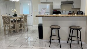 Una cocina moderna con gabinetes blancos, encimera de granito e iluminación colgante.