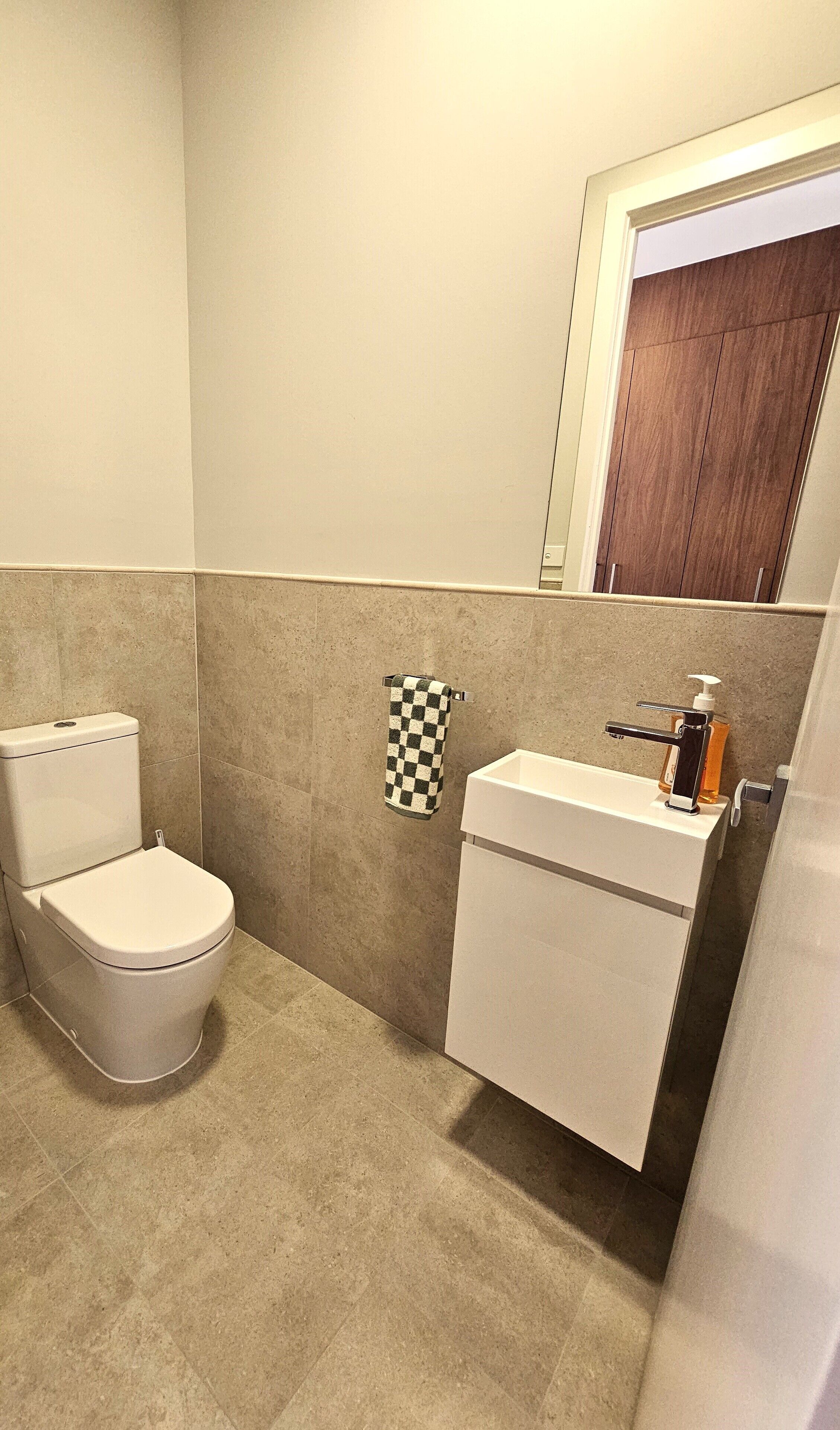 A bathroom with a toilet, sink, and a checkered towel hanging on the wall.