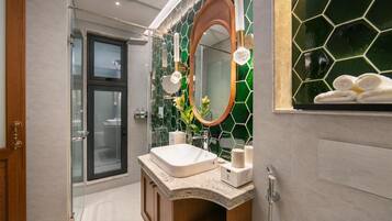 A modern bathroom with a glass shower enclosure, a freestanding sink, and a mirror with a hexagonal tile backsplash.