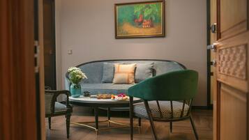 Una sala de estar con un sofá, un sillón verde, una mesa de centro y un cuadro en la pared.