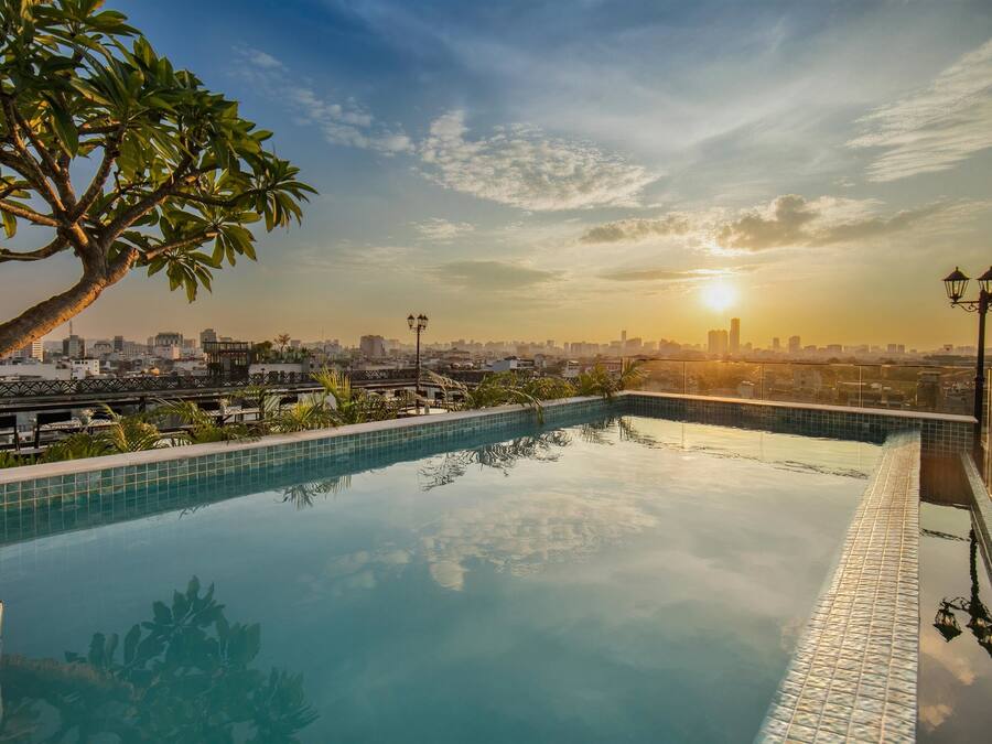 A rooftop infinity pool with a cityscape view at sunset.