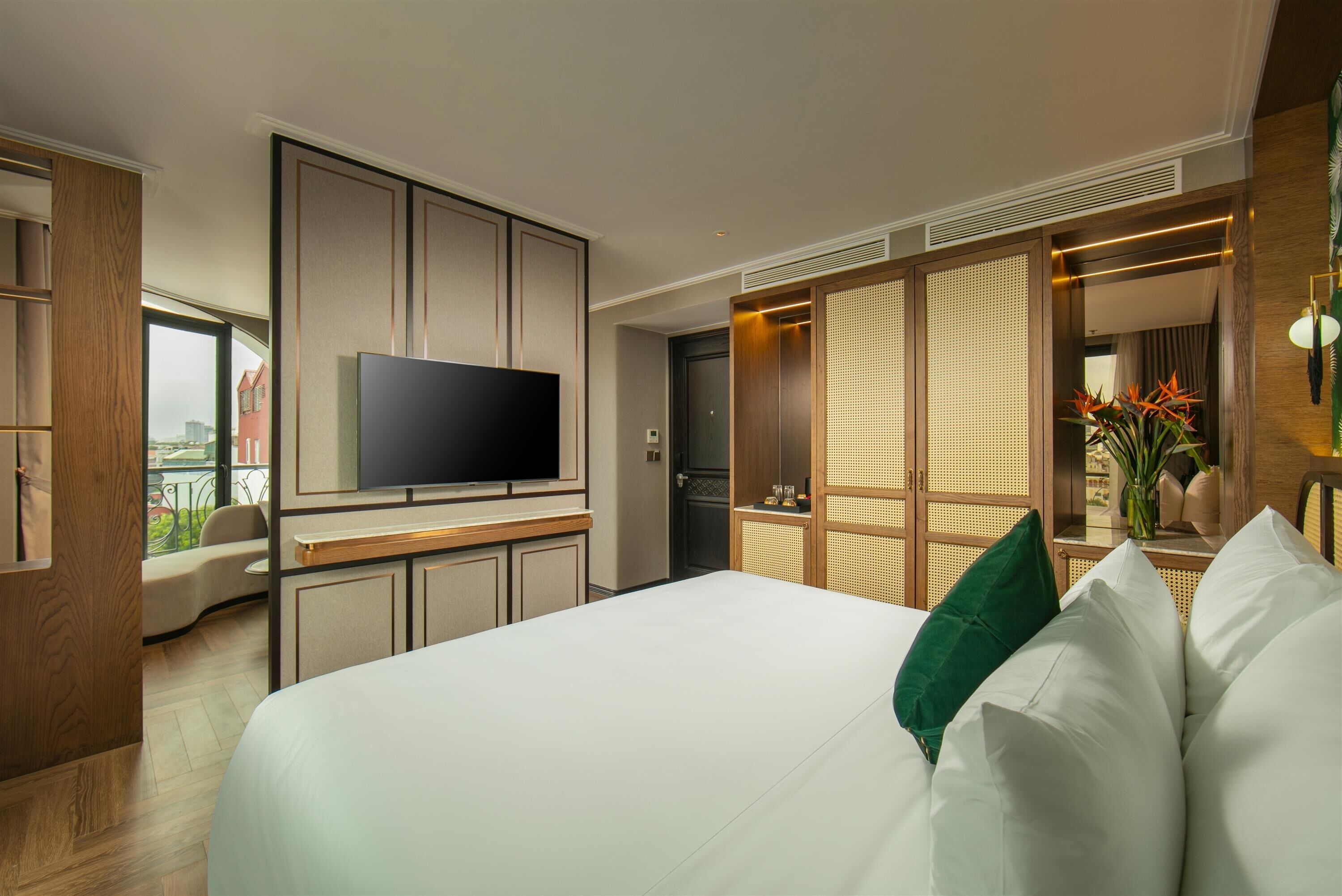 Habitación de hotel moderna con una cama grande, televisión de pantalla plana, zona de estar y vistas a la ciudad.