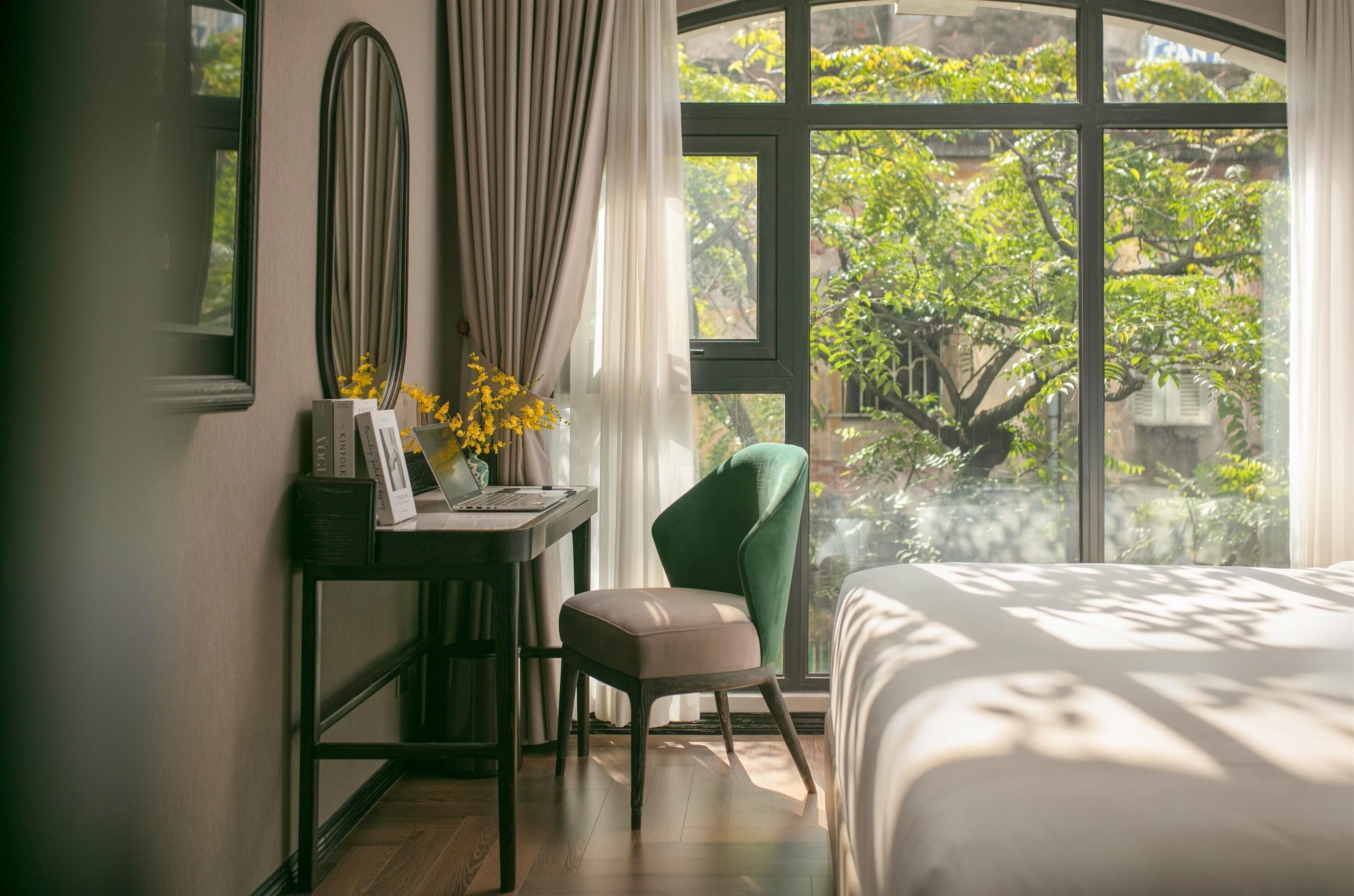 Un dormitorio con cama, escritorio, silla y ventana con vistas a follaje.