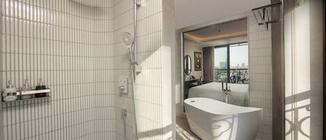 A modern bathroom with a freestanding bathtub, a shower with a handheld showerhead, and a vanity with a mirror.
