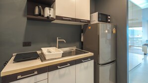 Une cuisine moderne équipée d’un four à micro-ondes encastré, d’un réfrigérateur en acier inoxydable, d’un évier et d’un plan de travail sur lequel se trouvent une bouilloire et un grille-pain.