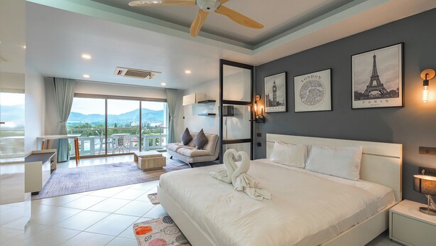 Une chambre d’hôtel moderne avec un grand lit, un balcon offrant une vue agréable et des œuvres d’art accrochées aux murs.