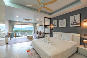 A modern hotel room with a large bed, a balcony with a view, and artwork on the walls. - 1BR Condo Pool & Mountain View C224 (Kathu)