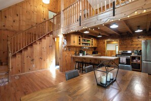 Interior de madera con escalera, cocina y comedor.