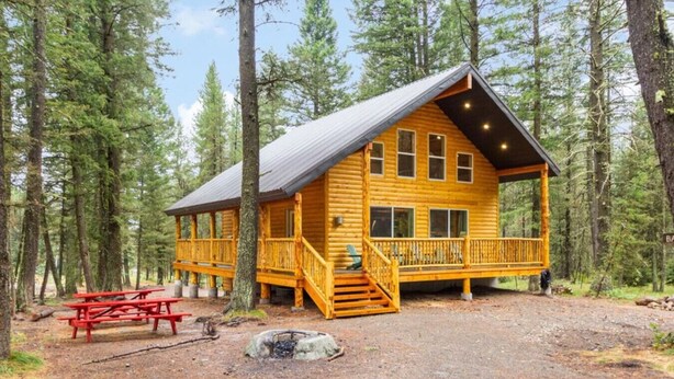 A wooden cabin with a porch, a picnic table, and a fire pit in a forest setting. - Barratt Lodge | Hot Tub | 35 mins to Yellowstone (Island Park)