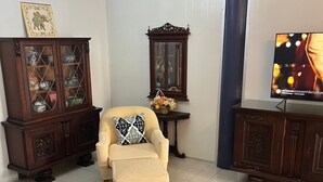 A living room with a sofa, a wooden bench, a television, a cabinet, and a chandelier. - Baan saen saran residence (แขวงคลองชักพระ เขตตลิ่งชัน)