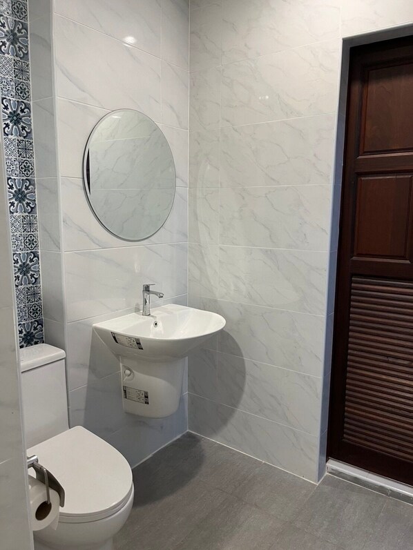 A modern bathroom with a toilet, sink, and mirror.