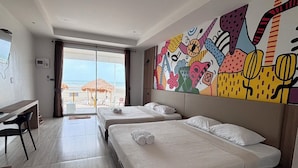 Une chambre d’hôtel avec deux lits, un bureau et une grande fenêtre donnant sur la plage.