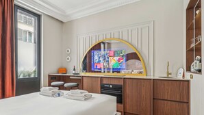 A hotel room with a bed, a desk with a computer, a sink, and a mirror. - Modern Apartment - 2P - Parc Monceau (Paris)