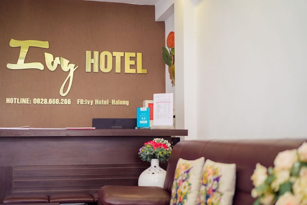 Un comptoir d’accueil avec une enseigne indiquant « Ivy Hotel » et un numéro de téléphone.