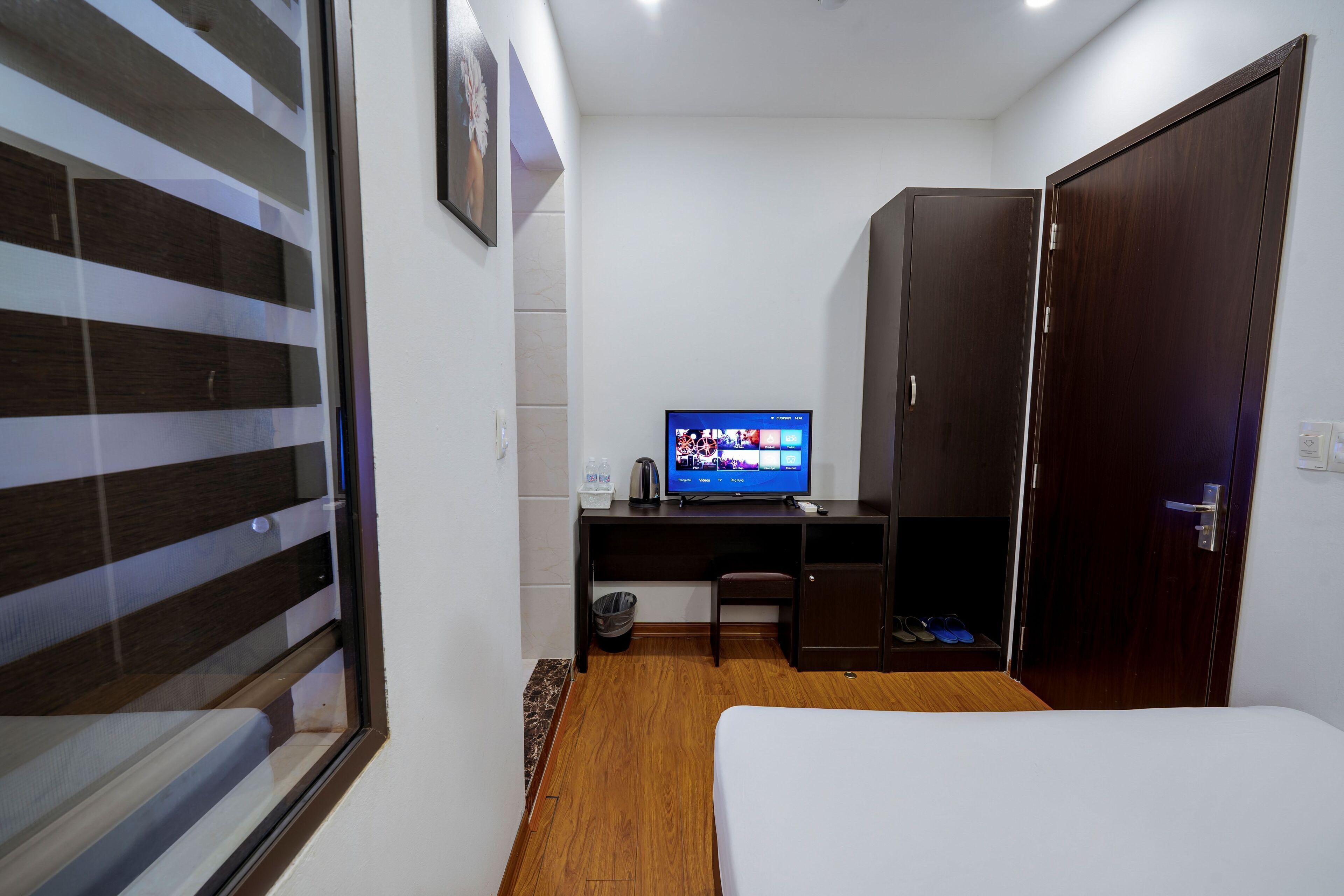 A hotel room with a bed, a desk with a computer, a TV, and a wardrobe.