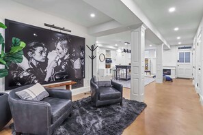 A modern living room with a large black and white painting, leather sofas, and a fluffy rug.