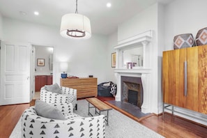 A modern living room with a fireplace, a wooden cabinet, and a dining area.