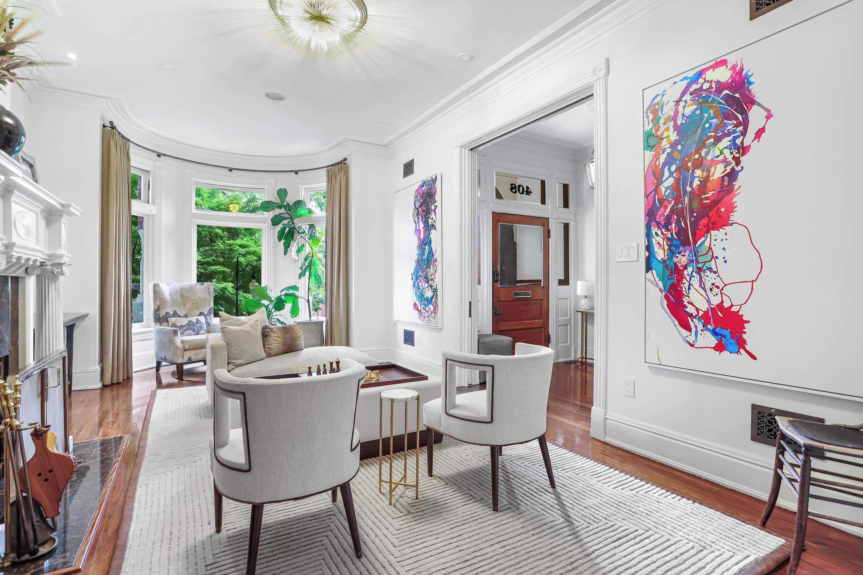 A spacious living room with a fireplace, a large abstract painting, and a view of the outdoors.