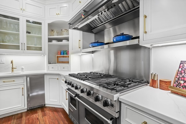 A modern kitchen with white cabinetry, stainless steel appliances, and a built-in oven.