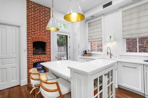 A kitchen with white cabinetry, a brick wall, and a large island.