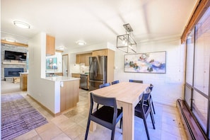 A modern kitchen with a dining area, a built-in oven, and a refrigerator.