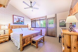 A bedroom with a wooden bed, a nightstand, a bench, a dresser, and a ceiling fan.