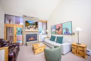 A living room with a fireplace, a sofa, a green armchair, and a wooden chest.