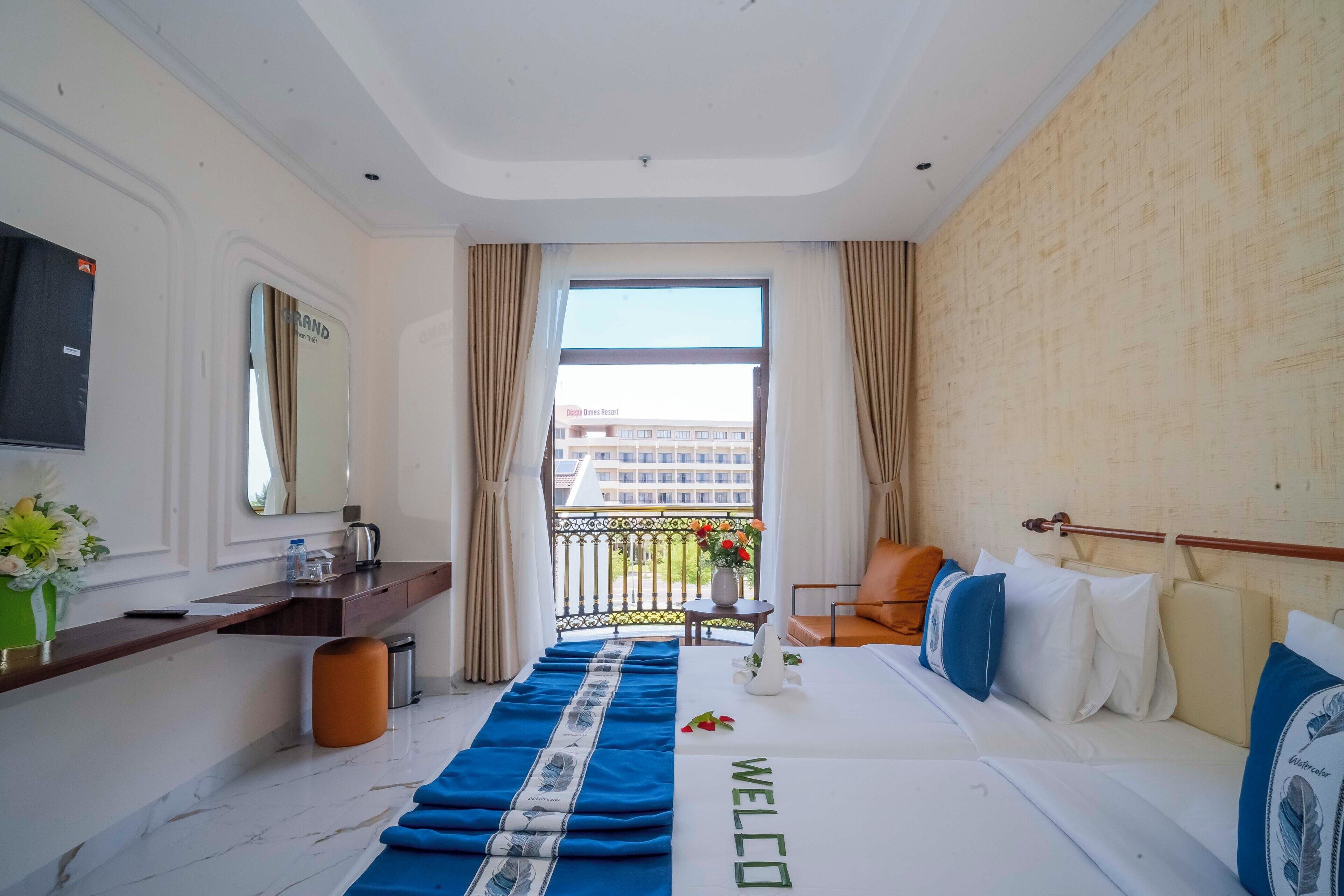 A hotel room with a bed, a desk, a TV, and a window with curtains.