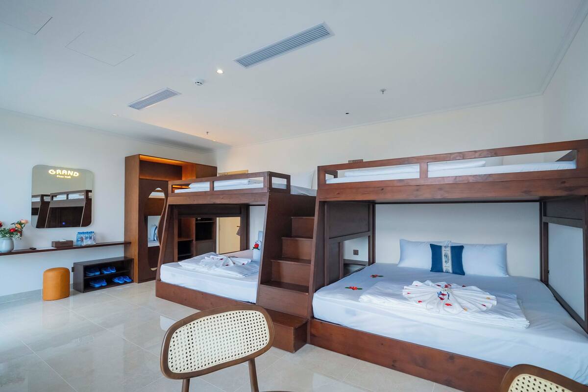 Une chambre d’hôtel avec des lits superposés, un bureau, une chaise, un miroir et un porte-chaussures.