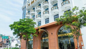 Een hotel met een grote, gebogen ingang, meerdere balkons en een bord waarop 'Coffee & Tea' staat.