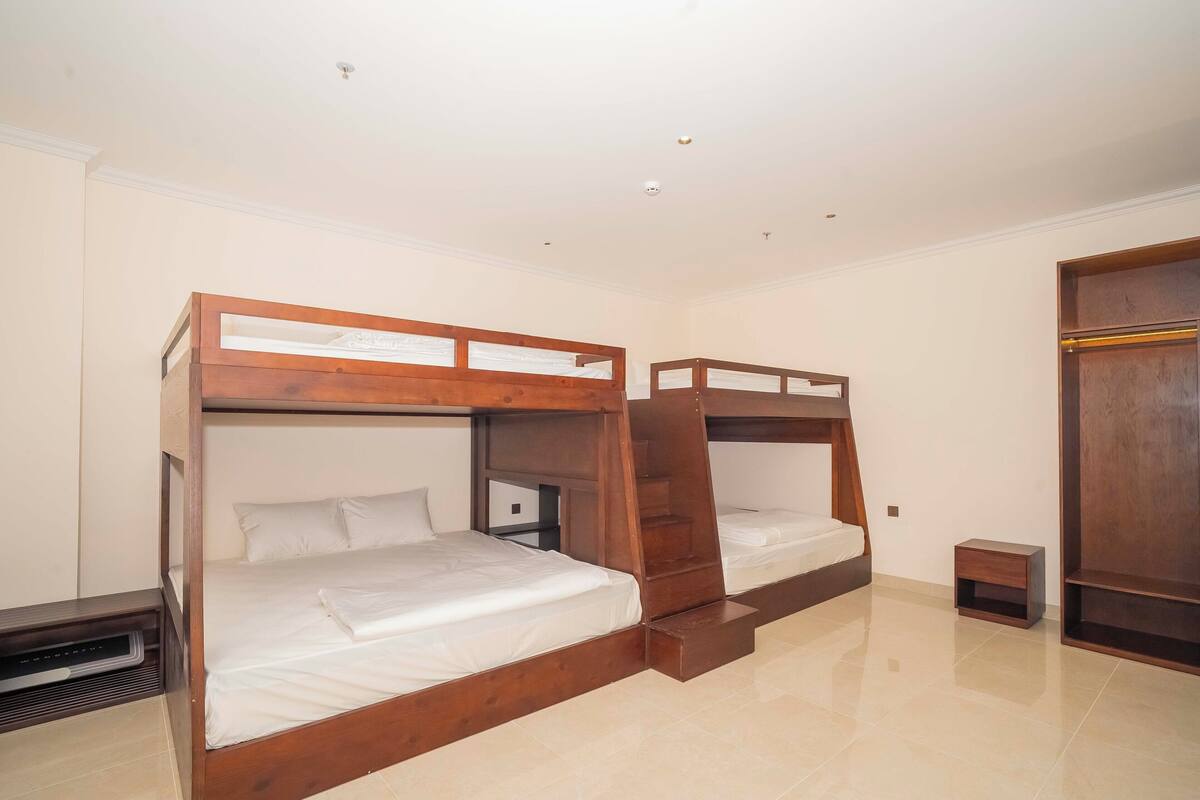 Une chambre avec des lits superposés, une petite table de chevet, une armoire et un radiateur.