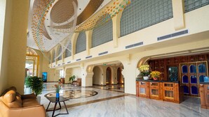 Een ruime lobby met een marmeren vloer, een receptiebalie en een zithoek.