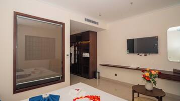 Een hotelkamer met een bed, een aan de muur bevestigde televisie, een tafeltje met een bloevas en een raam met uitzicht.