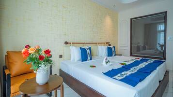 A hotel room with a large bed, a wooden headboard, a small table with a vase of flowers, and a large mirror on the wall.