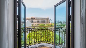 Een balkon met gedetailleerd zwart hekwerk en uitzicht op een gebouw met de tekst 'Dresden Hotel Resort'.