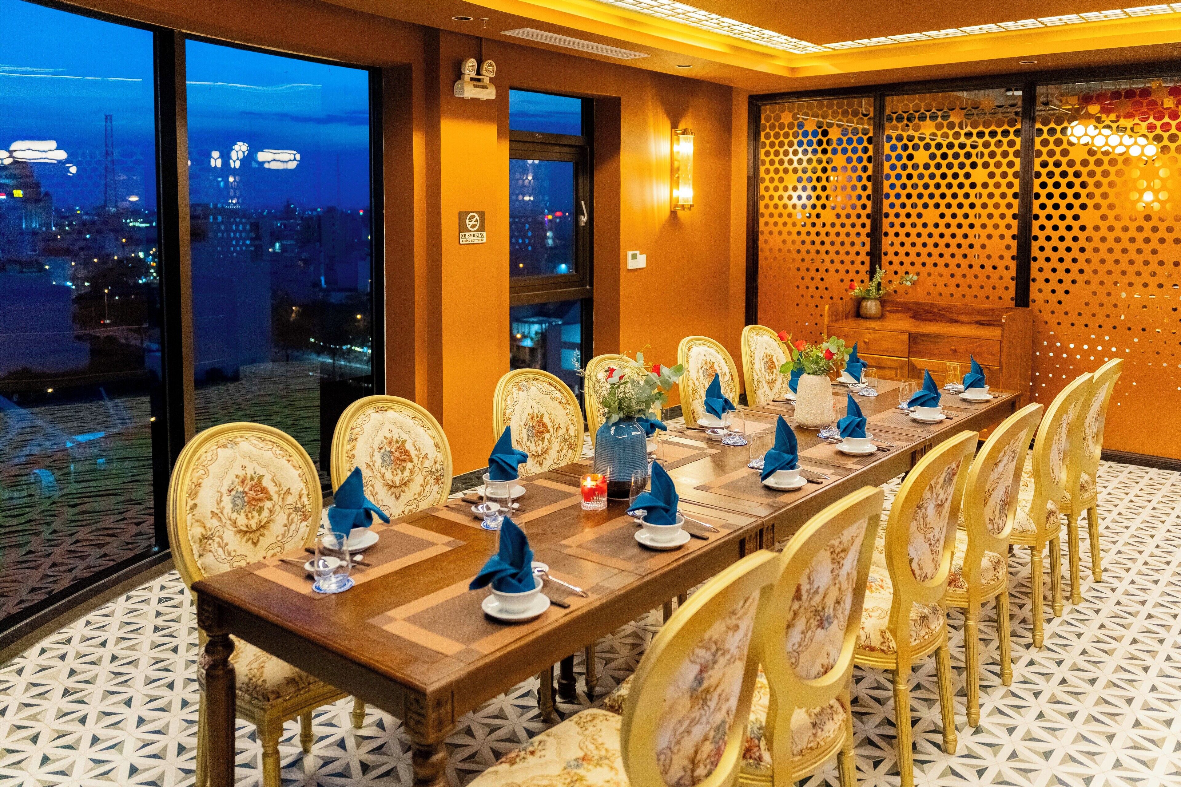 Una larga mesa de comedor con sillas, dispuesta para una comida, en una habitación con vista a la ciudad.